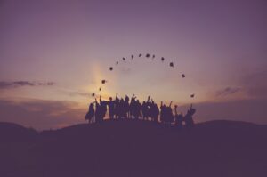 shadow picture of graduates in caps and gowns in distance at sunset
