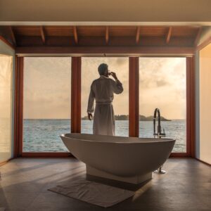 person from behind in bathrobe in luxury bathroom with giant white freestanding tub